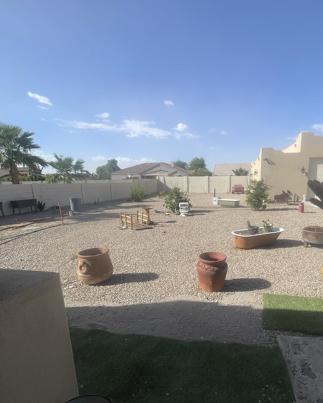 Casa Grande backyard before landscaping — bare gravel, scattered pots, and no walkways